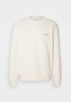 Cream-colored sweatshirt with a crew neck, ribbed cuffs, and hem. Features a small embroidered logo on the left chest. Soft texture.