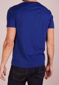 Kungsblå kortärmad t-shirt i mjuk bomullstyg, med rund halsringning och en avslappnad passform, matchas med mörka jeans.