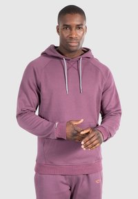 Felpa viola con cappuccio e lacci, polsini a coste e tasca a marsupio. Tessuto morbido con una texture uniforme e cordini leggeri a contrasto.