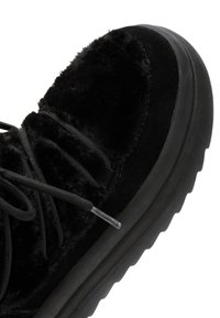Zwarte sneaker met een luxe bovenmateriaal, ronde neus, textuur en zwarte veters. Dikke zwarte zool met een geribbeld ontwerp.