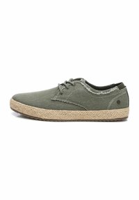 Zapatillas de lona verdes con suela de yute texturizada, diseño de cordones y acentos de borde deshilachado. Forma plana con punta redondeada y suela de goma.