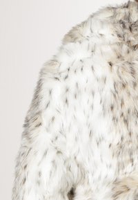 Faux fur jacket with a soft, textured surface. Predominantly white with grayish-brown speckled patterns. Features a plush, warm design.