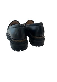 Scarpe slip-on nere in pelle con suola intermedia testurizzata, punta rotonda e suola in gomma. Dettagli di cucitura minimi sulla tomaia.