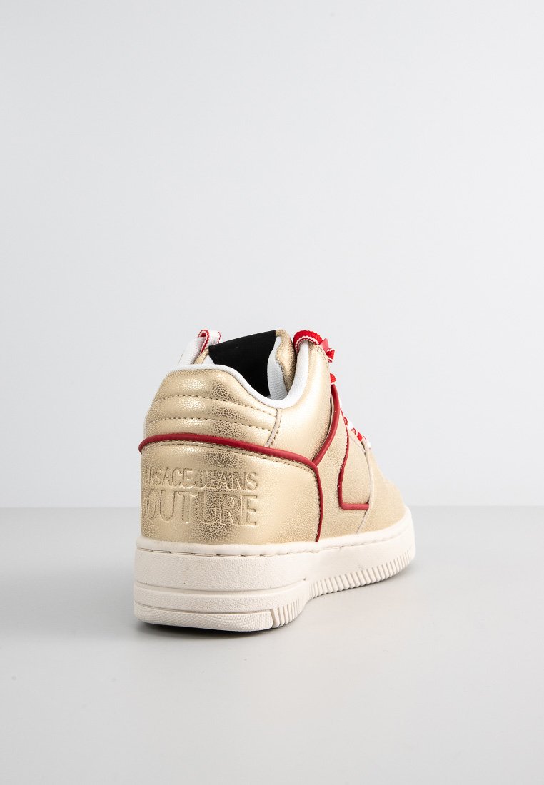 Sneaker sintetica dorata con accenti rossi, caratterizzata da una finitura testurizzata e logo "Versace Jeans Couture" in rilievo sul tallone. Design a collo basso.