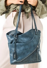 Sac à main en simili cuir bleu avec un design incurvé, poche zippée, motif perforé décoratif et bretelles ajustables.