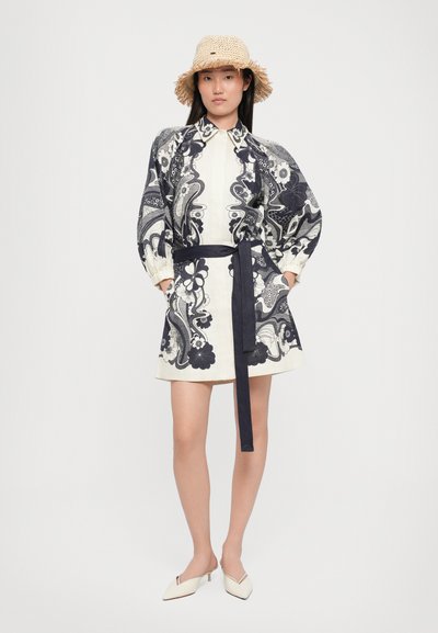 Rochie camasa de culoare ivorie cu model paisley albastru marin, avand un decolteu cu guler si mansete bufante. Include o curea asortata la talie si incaltaminte alba eleganta.