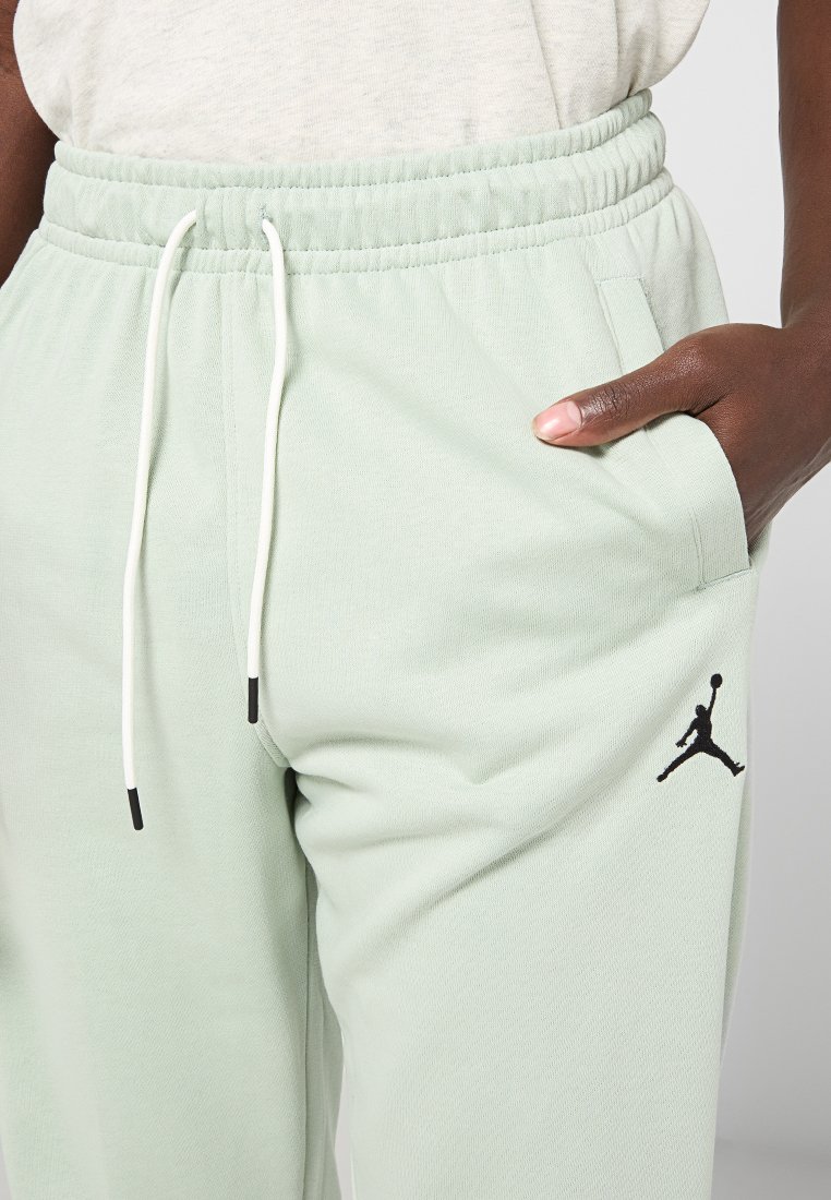 Pantaloni da jogging verde chiaro in morbido tessuto, con vita elasticizzata, cordini bianchi, tasche laterali e un accento di logo nero.