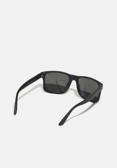 Ochelari de soare dreptunghiulari negri cu lentile întunecate, ramă din plastic mat, brațe subțiri și accente metalice lângă balamale.