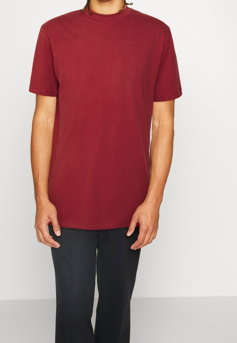 T-shirt marron à manches courtes en coton, avec un col rond et une coupe décontractée. Texture lisse sans motifs ni accents visibles.