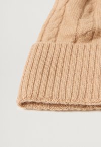 Beige knitted beanie with ribbed texture and cable design. Soft wool material, folded cuff at the bottom, smooth finish.