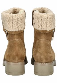 Botas de ante marrón hasta el tobillo con un puño de crema esponjoso, que presenta un detalle de botón y una suela de goma marrón. La textura es suave, con un diseño sólido.