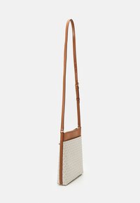 Torebka crossbody o jasnobeżowym płótnie, zdobiona powtarzającym się wzorem logo, z brązowymi skórzanymi akcentami i regulowanym paskiem. Smukły, prostokątny kształt.