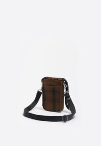 Bolso bandolera de cuadros marrones, hecho de un tejido duradero, con una parte superior de cordón, correa negra ajustable y detalles en acero inoxidable.