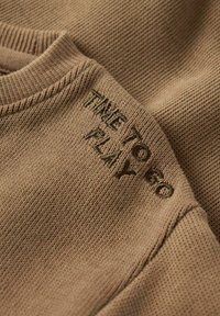 Brown textured knit fabric with a round neckline, featuring green embroidered text that reads "TIME TO GO PLAY."