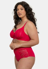 Ensemble de lingerie rouge comprenant un soutien-gorge avec broderie en dentelle et armatures, et un pantalon taille haute assorti avec des accents en dentelle sur les côtés.