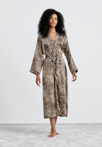 Robe en satin à imprimé léopard avec une taille à nouer, des manches longues et une longueur au genou, présentant une texture lisse et brillante.