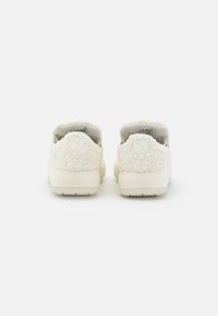 Biele plyšové obuv s jemnou textúrou, zaobleným tvarom a polstrovaným záznamom. Jemný logo detail na päte, masívna gumová podrážka.