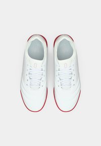 Zapatillas deportivas blancas con un diseño texturizado, que presentan una suela roja, cierre con cordones y una forma aerodinámica.