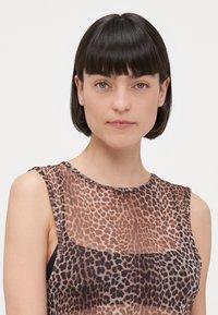 Top senza maniche con un design a stampa leopardata semi-trasparente in tonalità di marrone e nero, dalla texture liscia e scollo rotondo.
