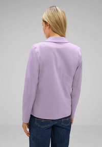 Light purple long-sleeve blouse with a collar, smooth texture, simple design, paired with dark blue jeans featuring visible stitching.