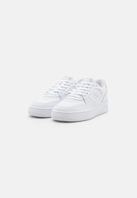White sneakers featuring smooth leather material, perforated toe box, round toe shape, flat lace-up design, and embossed logo on the side.