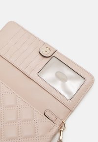 Interno di un portafoglio rosa chiaro con motivo a diamante, scomparti per carte, finestra trasparente per l'ID, hardware dorato e chiusura a scatto.