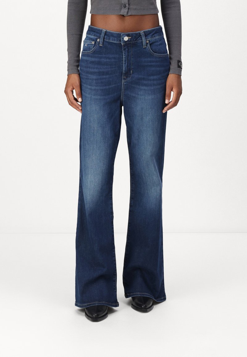 Φαρδιά σκούρα μπλε τζιν παντελόνια με κλασικό σχέδιο πέντε τσέπες, ψηλή μέση και φερμουάρ με κλείσιμο κουμπιού.