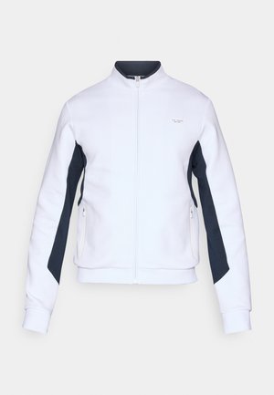 Biely sveter s vysokým golierom, predným zipsom a námorníckymi bočnými panelmi. Obsahuje zipsové vrecká a rebrované manžety pre textúru.