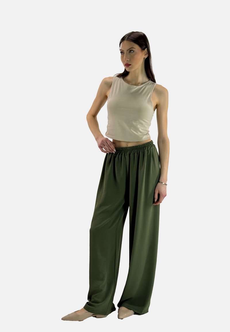 Beige mouwloze crop top gecombineerd met losse, high-waisted, donkergroene broek; zachte stof met een elastische tailleband en een ontspannen pasvorm.