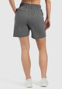 Grijze, knielange sportshorts met een elastische tailleband, zijzakken en een gladde textuur, gedragen met witte sneakers.