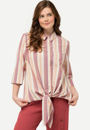 Gestreepte blouse in roze, wit en lavendel; met een kraag, knoopsluiting aan de voorkant en een gestrikt knoopje in de taille. Korte mouwen.