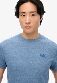 T-shirt a righe blu realizzato in cotone, con scollatura a girocollo e un piccolo logo sul lato sinistro del petto. Maniche corte e vestibilità comoda.