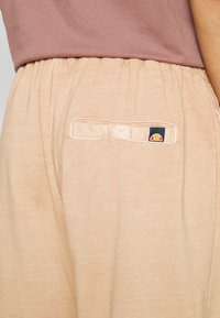 Ljust persikofärgade sweatpants med elastisk midja, med en liten bakficka som har en blå och orange logotagg. Mjuk bomullsblandning.