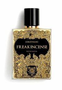 La bottiglia di Eau de Parfum FREAKINCENSE di Coreterno presenta un design in vetro trasparente con intricate decorazioni dorate, accenti neri e un tappo texturizzato.