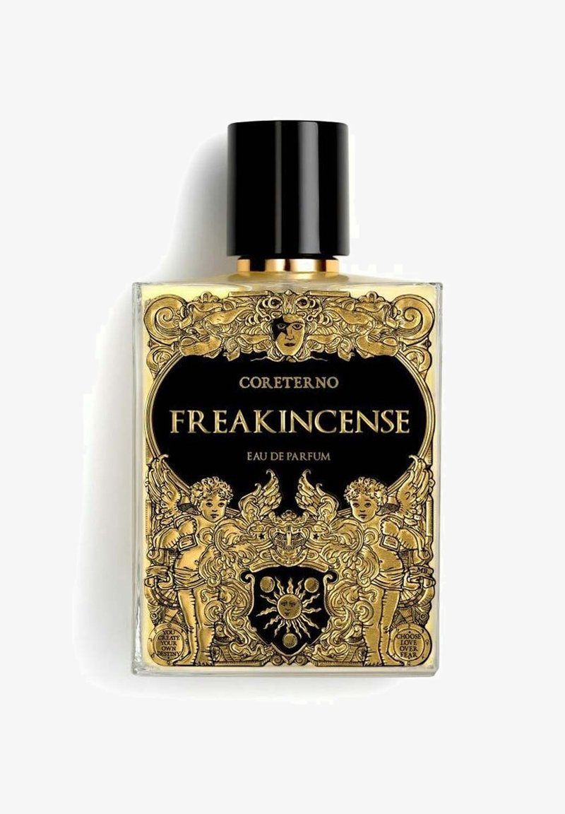 La bottiglia di Eau de Parfum FREAKINCENSE di Coreterno presenta un design in vetro trasparente con intricate decorazioni dorate, accenti neri e un tappo texturizzato.