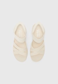Infradito beige con fasce elastiche intrecciate, tessuto morbido e testurizzato, design open toe e suola in gomma solida.