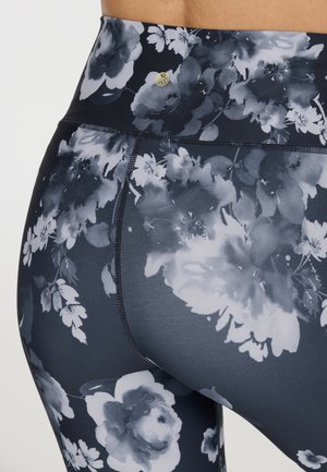 Leggings floraux bleu foncé avec des motifs de fleurs blancs et gris. Conception taille haute avec une taille plate et des détails de couture accentués.