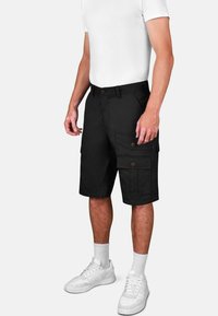 Schwarze Cargo-Shorts mit mehreren Taschen, einem Knopfverschluss und geradem Schnitt. Kombiniert mit weißen Sneakers und Sockensocken.