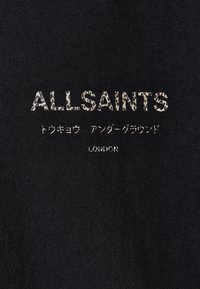 Zwarte stof met het logo "ALLSAINTS" in een luipaardprintstijl, naast Japanse tekst en "LONDEN" in eenvoudige witte letters.