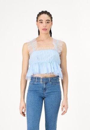 Cropped top azzurro chiaro realizzato in morbido tulle con spalline arricciate e orlo arricciato. Abbinato a jeans blu aderenti con una cintura in metallo argentato.
