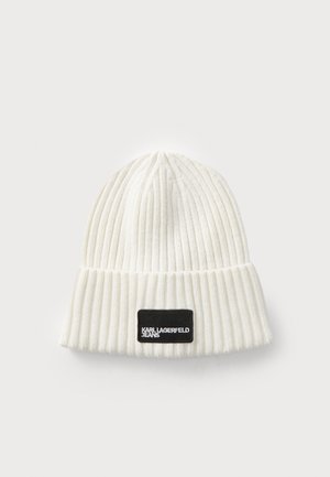 Gorro de punto blanco con textura de canalé y puño doblado. Presenta una etiqueta rectangular negra con letras blancas que dice "KARL LAGERFELD JEANS."