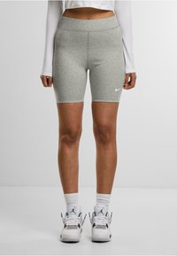 Shorts da bici grigi, aderenti, con vita alta e texture liscia, dotati di un logo Nike bianco sulla gamba sinistra.