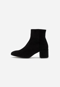 Botines de ante negros con punta redondeada, tacón bloque de altura media y una textura suave. Diseño sencillo sin herrajes ni acentos visibles.