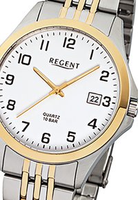Montre à quartz avec un cadran blanc, des accents dorés et des chiffres noirs. Bracelet en acier inoxydable argenté avec des détails rayés dorés. Affichage de la date à trois heures.