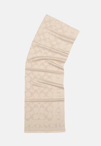 Beige tørklæde lavet af blødt stof, med et gentaget logo-mønster i en lidt mørkere nuance og frynset kant for tekstur.