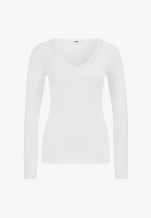 Fehér, hosszú ujjú blúz V-nyakkivágással, díszes csipkével a szegélyén, sima anyagból készült, testhez simuló fazon. Nincsenek minták vagy kiegészítők.