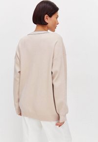 Suéter beige de gran tamaño hecho de una tela suave, con un escote redondo y mangas largas, y con un bajo y puños de canalé.
