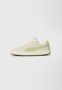 Cream canvas sneakers with green suede accents, round toe, flat laces, gold branding, and a textured rubber sole.