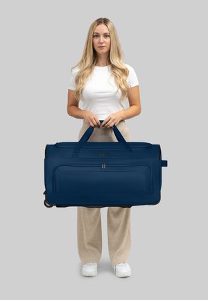 Borsa da viaggio navy realizzata in tessuto resistente, con due manici e una texture liscia; dotata di ruote e di una tasca con zip sul davanti.