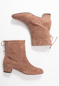 Bruna mockaläder ankelskor med låg klack, med en avsmalnande tå och en dekorativ rosett på baksidan för justerbar passform. Slät textur.